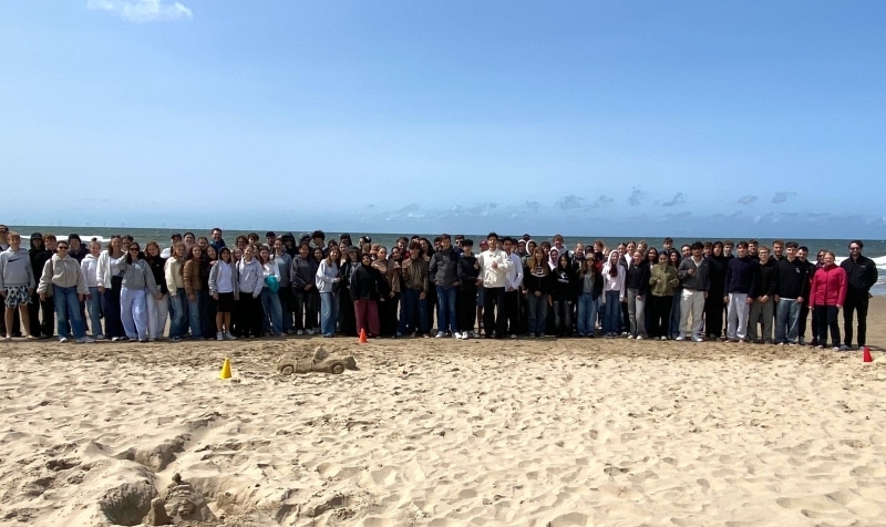Gruppenbild von einer großen Gruppe an Jugendlichen am Strand.
